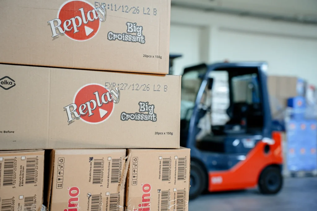 Cartons of Replay Big Croissant on the warehouse floor beside a forklift